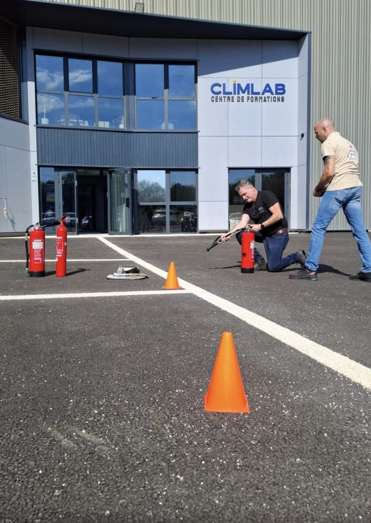 Stagiaire à genou utilisant un extincteur lors d’un exercice pratique de formation incendie MFP84, formateur en supervision